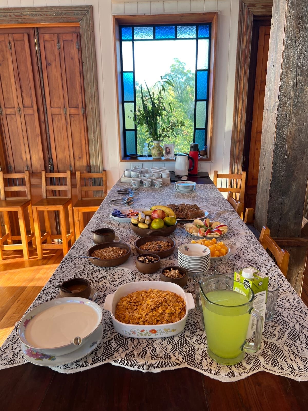Mesa de desayuno con frutas, granola y jugo junto a un ventanal